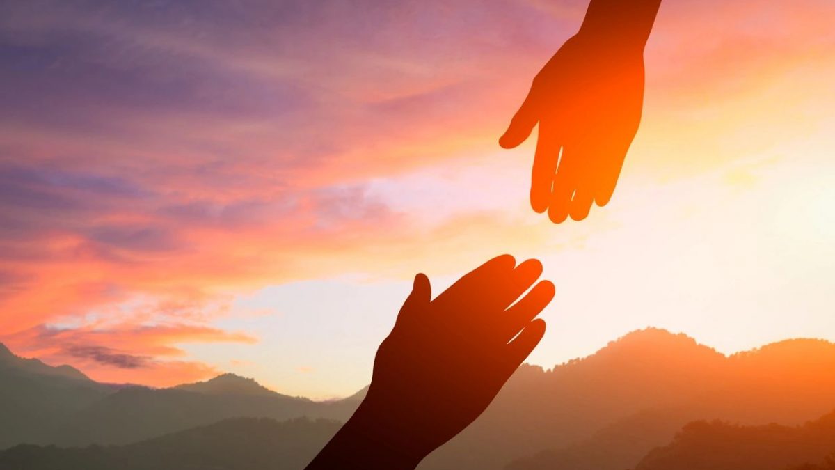 a photo of two hands reaching for each other in the sunset